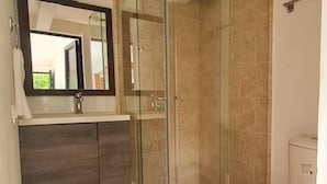A modern bathroom with a glass-enclosed shower, a white toilet, and a dark wood vanity.