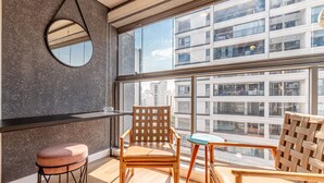 A modern interior with a large window, a round mirror, and two wooden chairs.