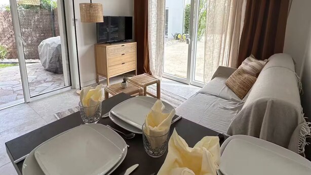 A dining area with a table set for four, a sofa, and a TV in the background.