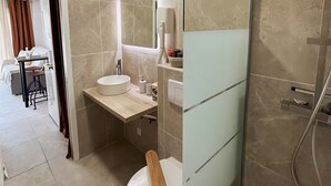 A modern bathroom with a wooden vanity, a white sink, and a toilet.