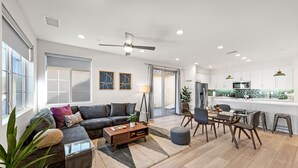 A spacious living room with a sofa, coffee table, and dining area. - Gated PGA West 2023 New Build (EV Charger) (La Quinta)