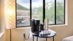 Una macchina da caffè su un tavolo vicino a una finestra con vista su un parcheggio e alberi.