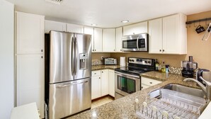 Una cucina moderna con elettrodomestici in acciaio inossidabile, piani in granito e mobili bianchi.