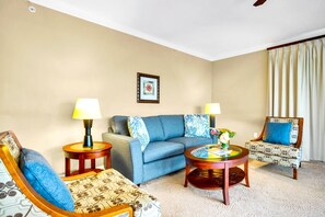 A living room with a sofa, two armchairs, a coffee table, and two lamps.