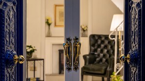 A room with a white door, a black upholstered chair, a lamp, and a staircase with a decorative railing.