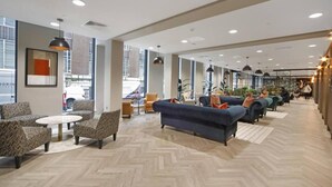 Un hall d’entrée spacieux, doté de meubles modernes, de grandes fenêtres et d’un parquet disposé en motif chevrons.