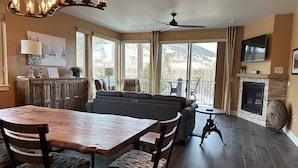 A dining area with a wooden table and chairs, a sofa, and a fireplace. - Luxury Dillon Ski Condo – 2 Master Suites, Heated Garage + Near 7 Ski Resorts (Dillon)