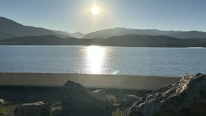 A lake with mountains in the background and the sun reflecting on the water. - Luxury Dillon Ski Condo – 2 Master Suites, Heated Garage + Near 7 Ski Resorts (Dillon)