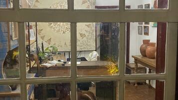 A room with a window with a grid pattern, a chandelier, and various items on shelves and tables.