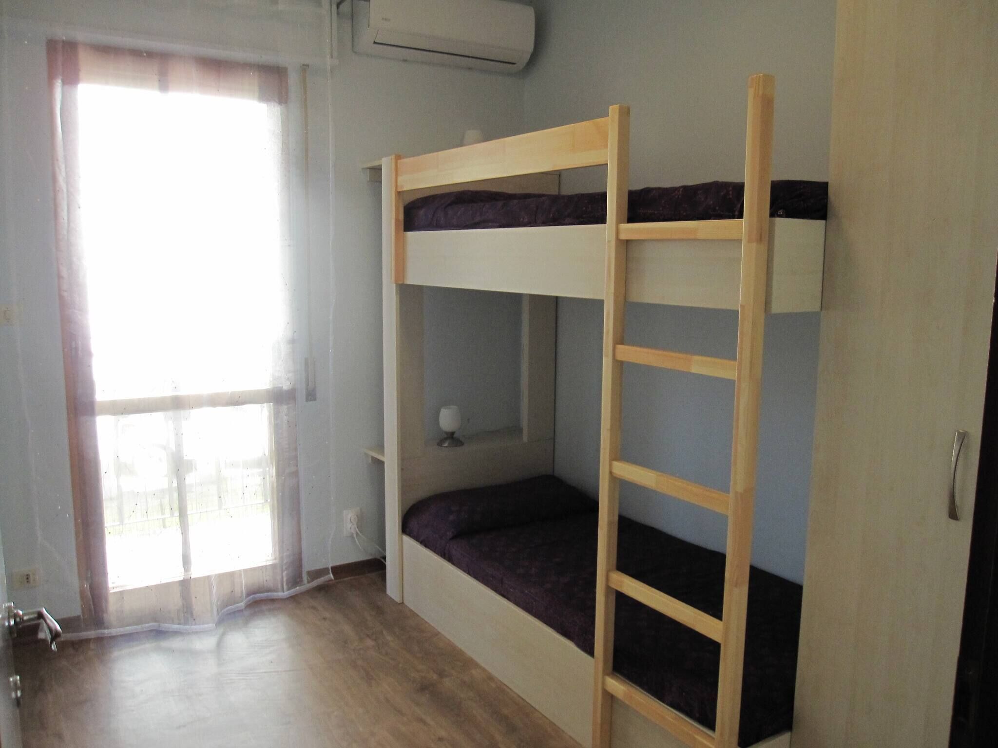 Camera con letto a castello, una scala in legno, una finestra con tende e una porta.
