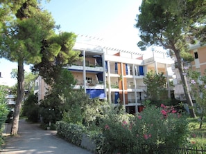 A multi-story hotel with balconies, surrounded by trees and greenery. - Amazing Apartment With Seaview Terrace (Grado)