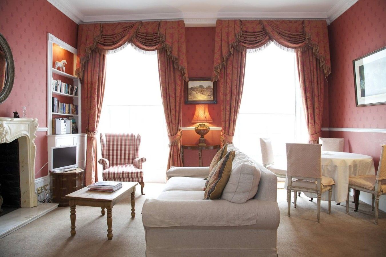 A traditional living room with a fireplace, a sofa, a chair, a table, and a bookshelf.