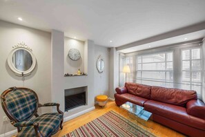 A living room with a fireplace, a sofa, a chair, and a round mirror.