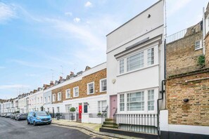 Une rangée de maisons mitoyennes, avec un fourgon bleu garé dans la rue.