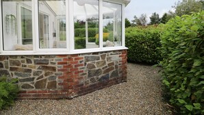A conservatory with a stone and brick exterior, a gravel path, and surrounding greenery. - Rhydygroes (Lampeter)