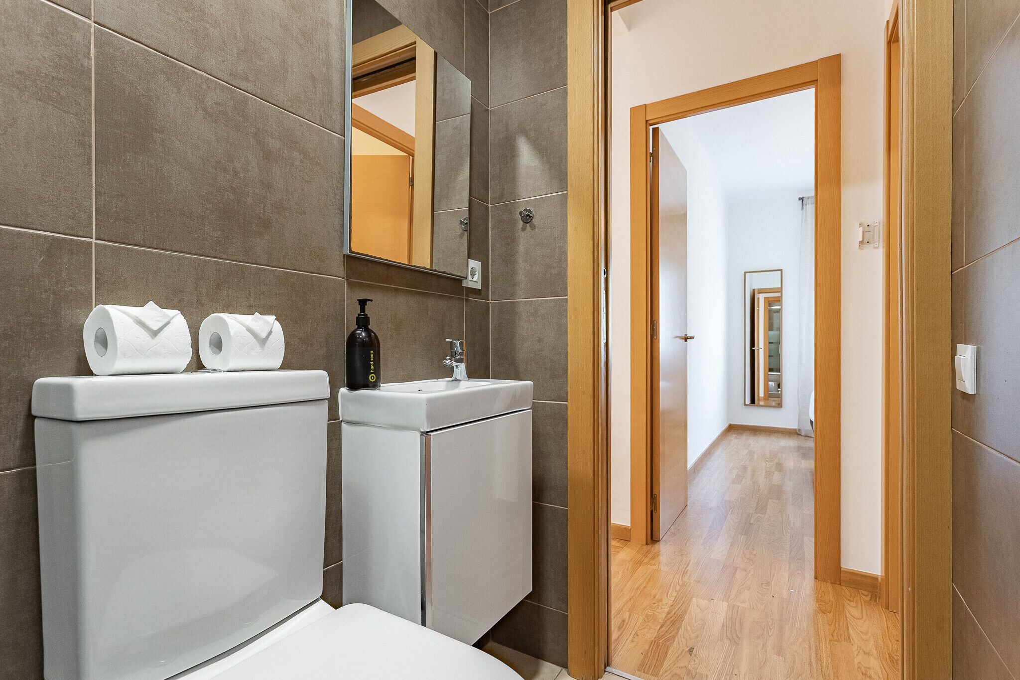 Un baño moderno con inodoro, lavamanos y espejo.