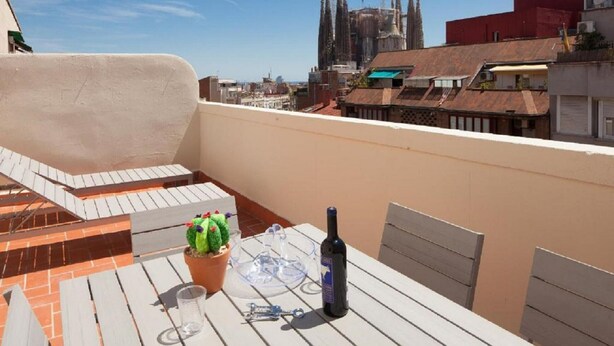 Eine Dachterrasse mit Tisch, einer Flasche und einem Blumentopf.