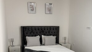 Een slaapkamer met een groot bed, twee nachtkastjes en een marmeren vloer.