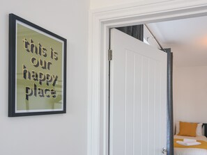 A framed sign with text, a white door, and a bed with a yellow pillow. - Lyme Zest (Lyme Regis)