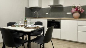 Une cuisine moderne avec une table à manger, des chaises, un vase de fleurs et une bouteille de vin.
