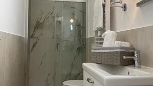 Une salle de bain moderne avec une douche à parois de verre, des toilettes et un meuble-lavabo doté d’un miroir et d’un porte-serviettes.