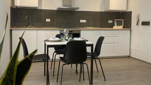 Une cuisine moderne avec un coin repas, comprenant un îlot central, un revêtement mural foncé et un parquet en bois clair.