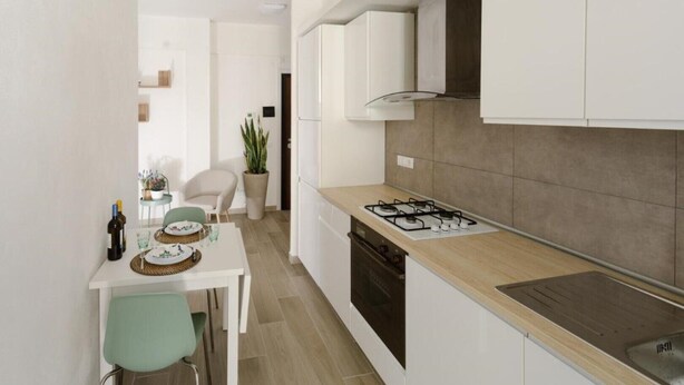A modern kitchen with white cabinets, a gas stove, and a dishwasher. There is a dining area with a table and chairs. - Terre d'aMare Liguria (La Spezia)