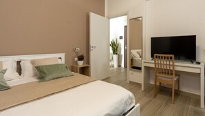 A bedroom with a bed, bedside table, TV, and desk with a chair. - Terre d'aMare Liguria (La Spezia)