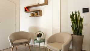 A modern living room with two beige armchairs, a small table with a potted plant, and a large potted plant against the wall. - Terre d'aMare Liguria (La Spezia)