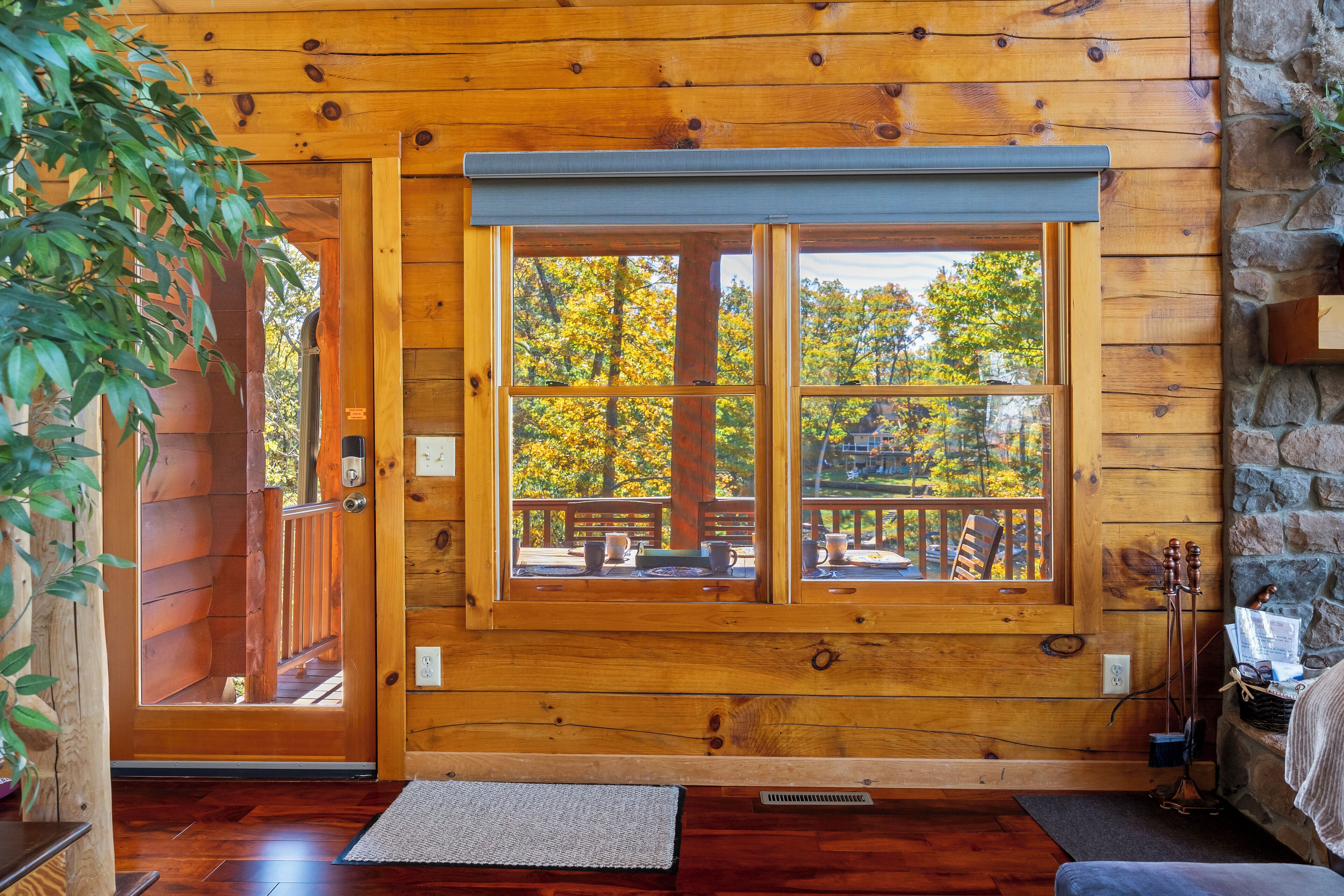 L’intérieur d’un chalet en bois, avec une grande fenêtre, des murs en bois et une cheminée en pierre.