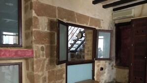 A room with stone walls, a wooden cabinet, a small wooden chest, and a window with a metal railing. - Authentic Escape: Tosca Stone Studio in Javea (Xàbia)