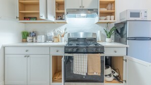 A modern kitchen with white cabinetry, a gas stove, a microwave, and a refrigerator. - Spring 25% Discount is here, 1King bed, Near NYC (Hoboken)