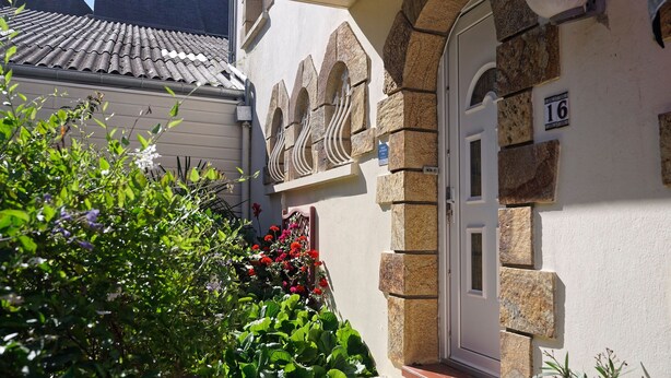 A building with a stone facade, a white door with the number 16, and a tiled roof.