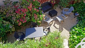 A patio area with outdoor furniture, a red lattice fence, and various plants.