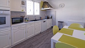A modern kitchen with white cabinets, a microwave, a sink, and a dining area with a table and chairs.