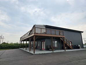Un bâtiment à deux étages doté d’un balcon, d’un espace extérieur couvert aménagé en coin salon et d’un escalier menant à l’étage supérieur.