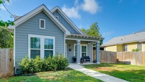 A two-story house with a covered porch, a fenced backyard, and a well-maintained lawn.