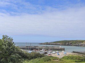 Un puerto costero con barcos amarrados, un muelle y un paisaje rocoso al fondo.