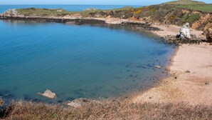 Un paisaje costero con aguas azul cristalino, playa arenosa y acantilados rocosos.