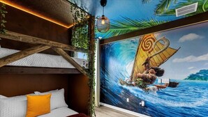 Quarto com um mural de uma cena náutica, cama com almofadas brancas e laranja, e estrutura de teto em madeira.
