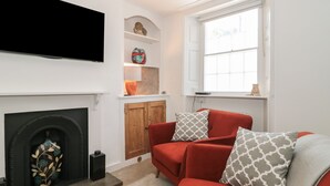 Ein Wohnzimmer mit Kamin, einem roten Sofa und einem an der Wand befestigten Fernseher.