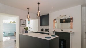 Eine moderne Küche mit einer zentralen Kochinsel, Pendelleuchten, einem eingebauten Backofen und einem Kamin.