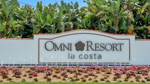 Une enseigne pour l’hôtel Omni Resort, ornée d’une bordure décorative et précédée d’un jardin fleuri.