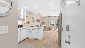 Une cuisine moderne avec des meubles blancs, des luminaires suspendus et une vue sur l’extérieur.