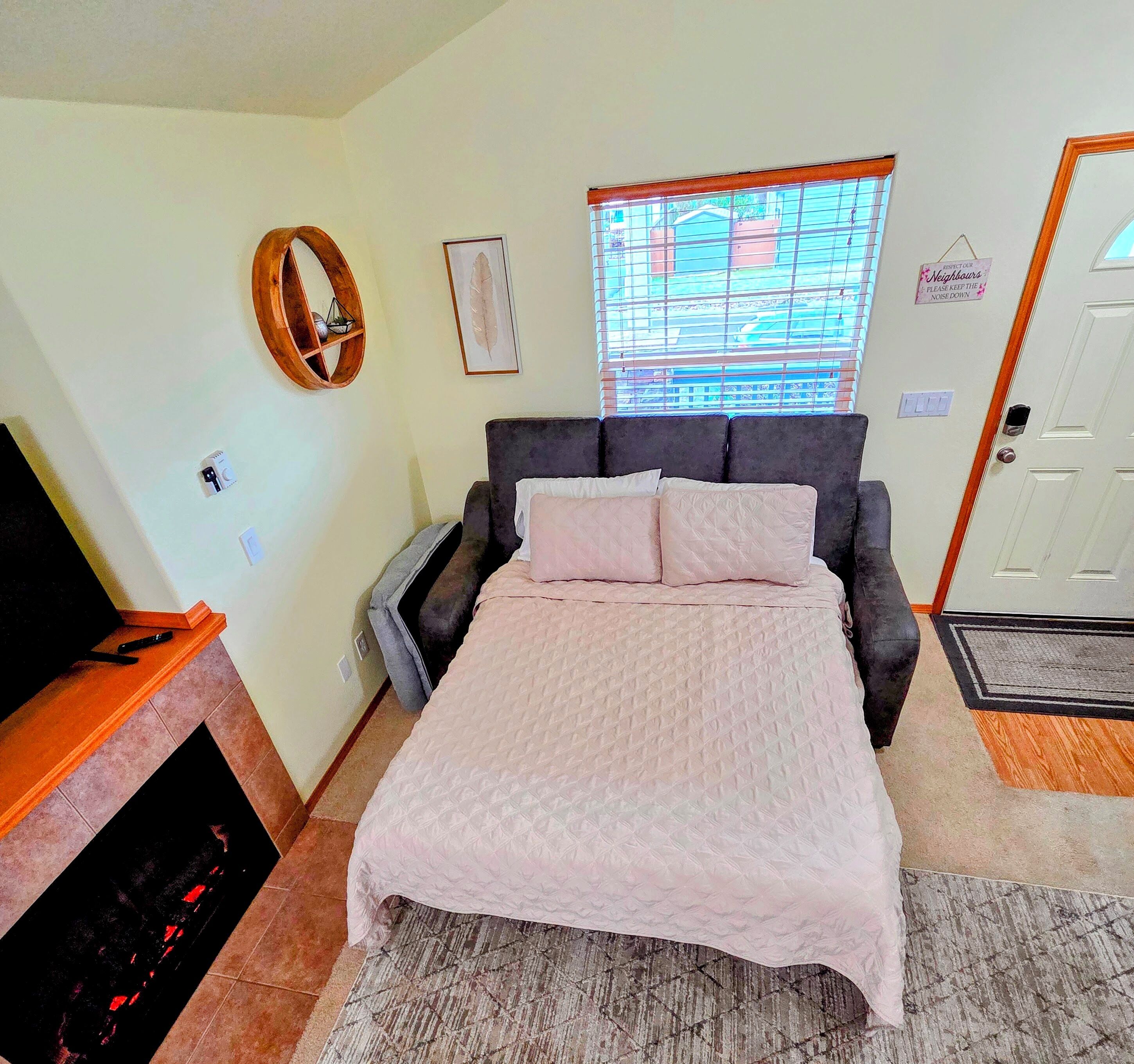 A bedroom with a bed, a TV, a fireplace, a window, and a door.