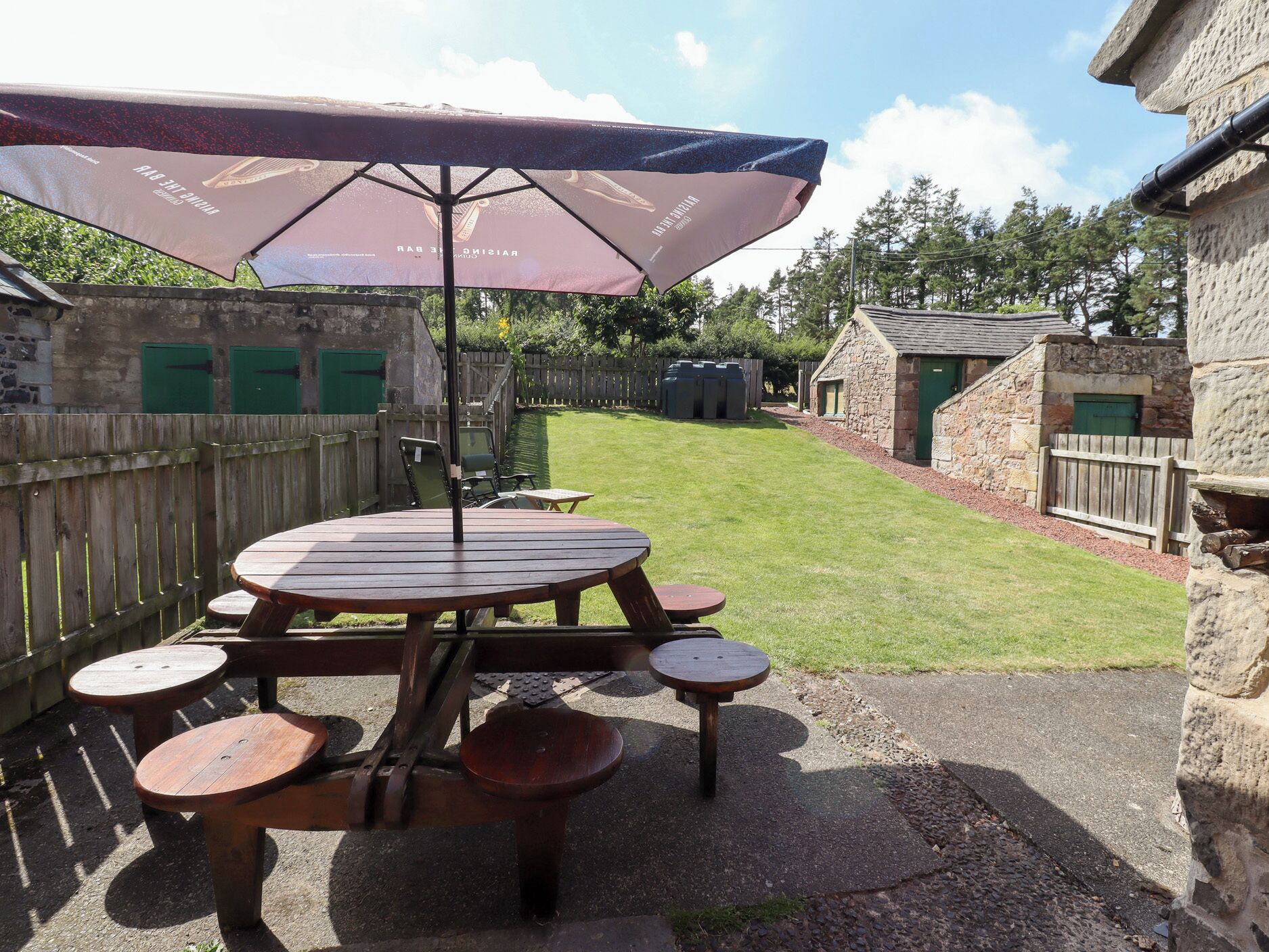 A picnic table with a canopy, surrounded by stone walls and a grassy yard.