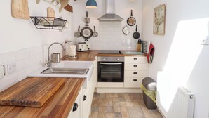 Una cocina moderna con armarios blancos, encimera de madera, un lavamanos, una estufa y lámparas colgantes azules.