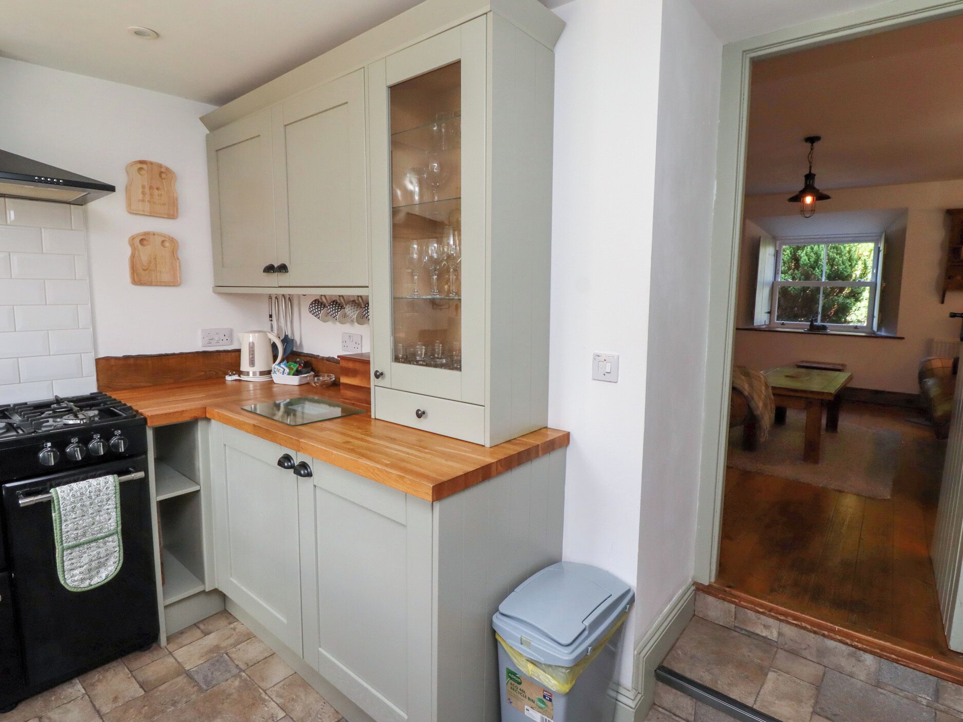 A kitchen with white cabinets, a black stove, and a wooden countertop.