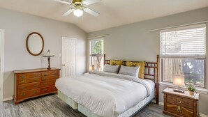 Un dormitorio con cama, cómoda, mesita de noche y ventilador de techo.