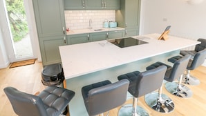 A modern kitchen with a central island, bar stools, and a view of the outdoors. - James' Place (Falmouth)